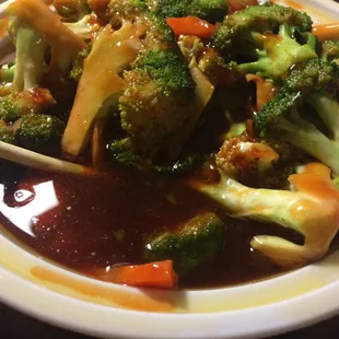 Broccoli with garlic sauce sitting in a bowl full of oil.