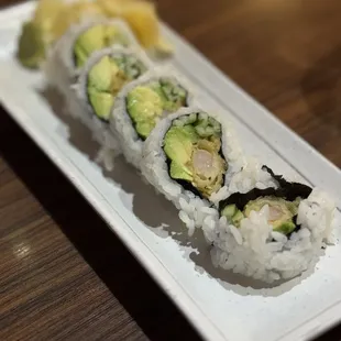 a plate of sushi rolls on a wooden table