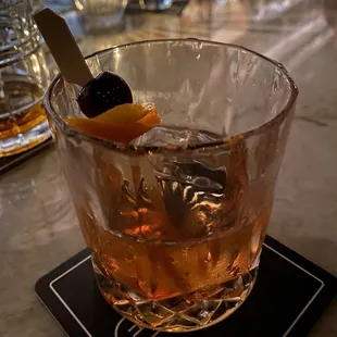 a drink in a glass with an orange garnish