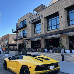 a yellow sports car parked in front of a hotel