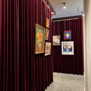 a hallway with red curtains and paintings