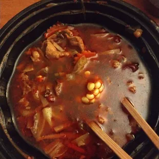 a bowl of soup with chopsticks