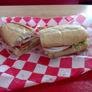 two sub sandwiches on a red and white checkered paper