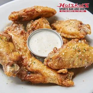 a plate of chicken wings with a dipping sauce