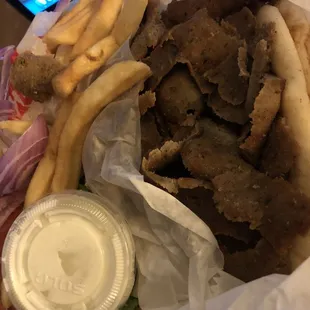 Dried out overcooked gyros meat on plate with two pitas, fries and salad.