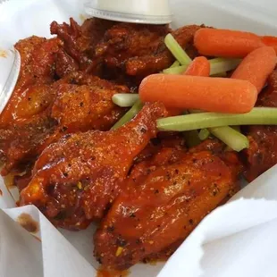 a basket of chicken wings with carrots and celery