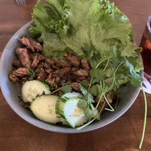 a bowl of salad with meat and cucumbers