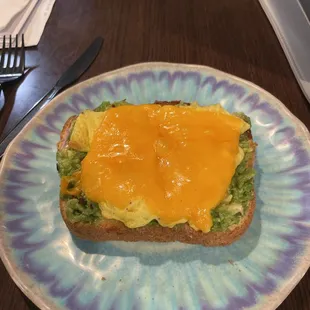 Avocado toast with a scrambled egg and sharp cheddar cheese! Yum