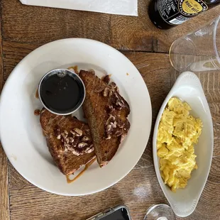 a plate of french toast, scrambled eggs, and a bottle of beer