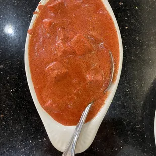 a spoon in a bowl of tomato sauce