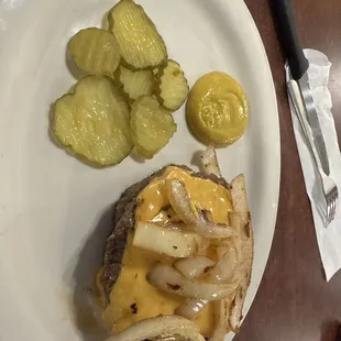 Two cheese burger patties with mustard, grilled onions and pickles.