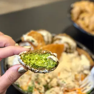 a hand holding a piece of falafel