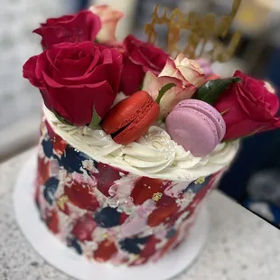 a cake decorated with roses and macaroons