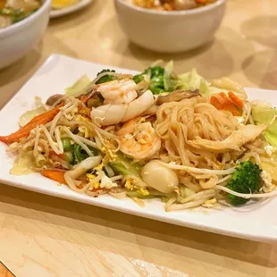 a plate of noodles with shrimp and vegetables