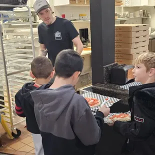 Waiting in line to have their pizzas baked