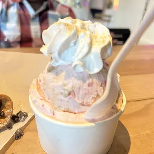 a child sitting at a table with a bowl of ice cream and a spoon