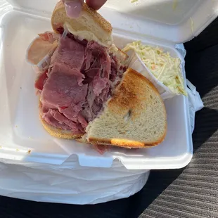 a person holding a sandwich in a styrofoam container