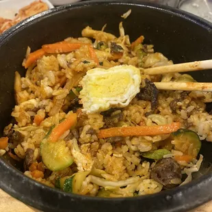 Beef Bibimbap with a bite of an egg roll on top.