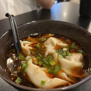 a bowl of soup with chopsticks