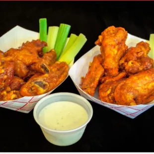 two baskets of chicken wings with celery and ranch dressing