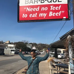 ows a woman standing in front of a sign that says need no teef to eat my beef