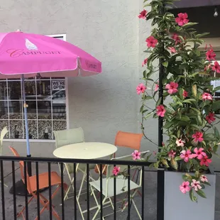 a patio with a table and chairs and a pink umbrella