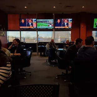 people sitting at tables watching tvs