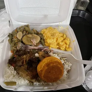 Smothered chicken plate with Mac and cheese, gravy rice, and green beans.