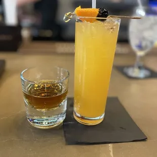 a glass of orange juice and a glass of whiskey