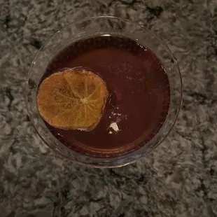 a glass of wine with a slice of orange in it