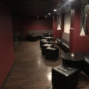 a long room with black leather seating and red walls