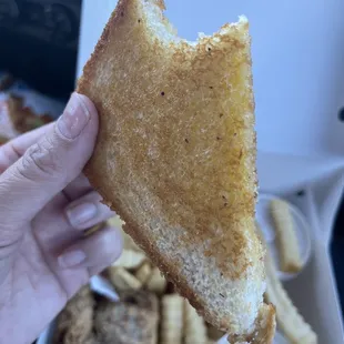 a hand holding a half eaten sandwich