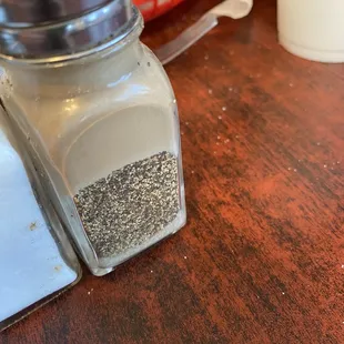 Pepper shaker, greasy on the top, sides and unclean inside exposing years of it being refilled and not cleaned in between.