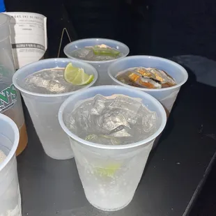 a row of plastic cups filled with ice and lime slices