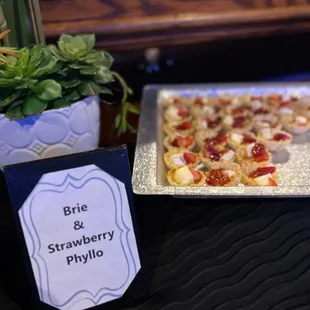 a plate of pizza and a sign that says brie and strawberry phyllo