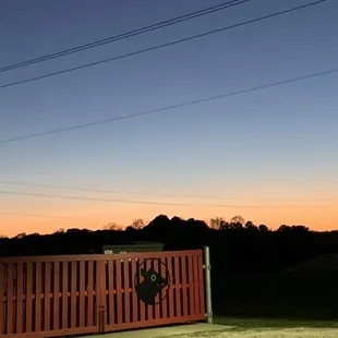 a fenced pasture with a gate at sunset