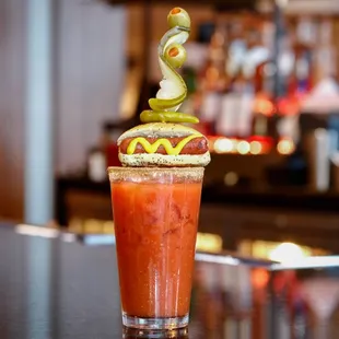 a bloody drink with a hot dog on top