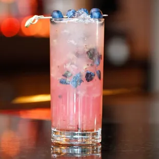 a pink cocktail with blueberries