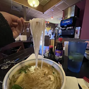 a person dipping noodles into a bowl
