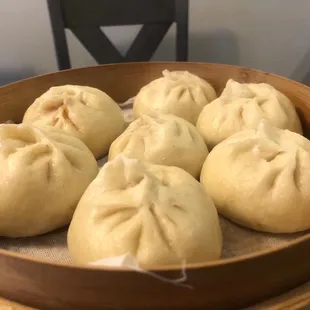 six steamed dumplings in a wooden bowl