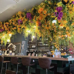 a bar with flowers hanging from the ceiling