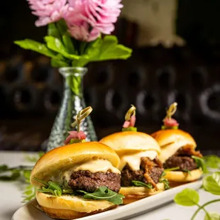 a plate of sliders and a vase of flowers