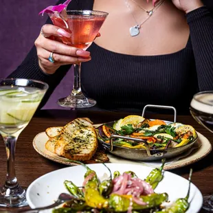 a woman sitting at a table with food and drinks