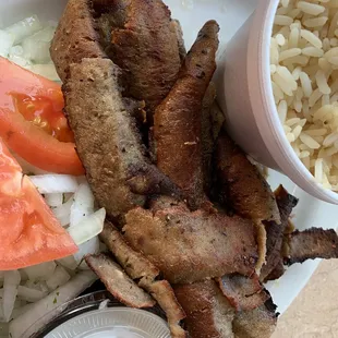 a plate of meat, rice, tomatoes, and a salad