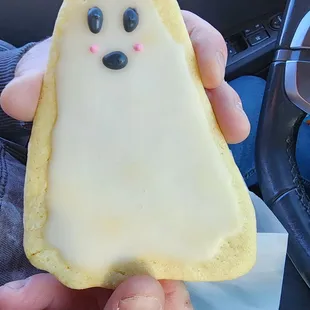 a hand holding a frosted ghost cookie