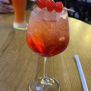 a drink in a glass with cherries on the rim