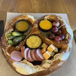 a pretzel with sausage, cheese, and pickles