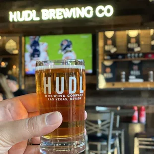 Taster glass with the merch wall &amp; brewery sign in background