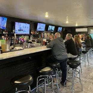 people sitting at the bar watching tvs