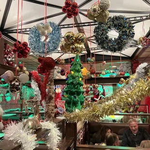 a woman sitting in a booth with christmas decorations hanging from the ceiling
